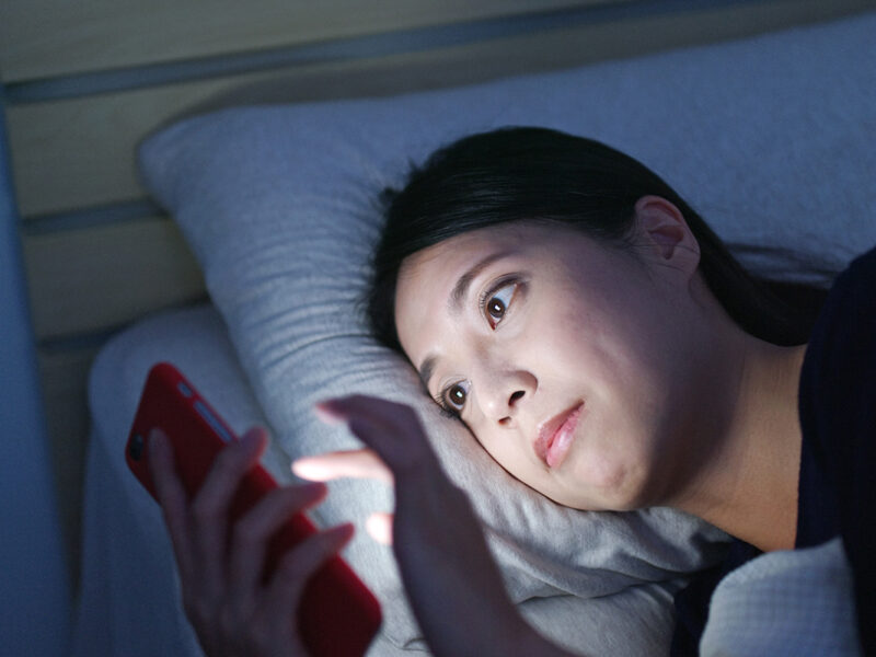 Woman watch on cellphone and lying on bed at night