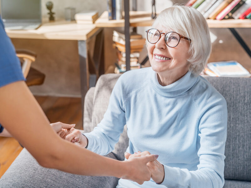 Cropped image of female professional caregiver taking care of elderly woman at home