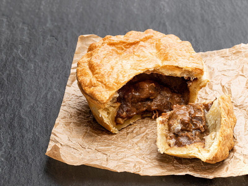 Puff pastry steak pie on baking paper on black stone backgroung